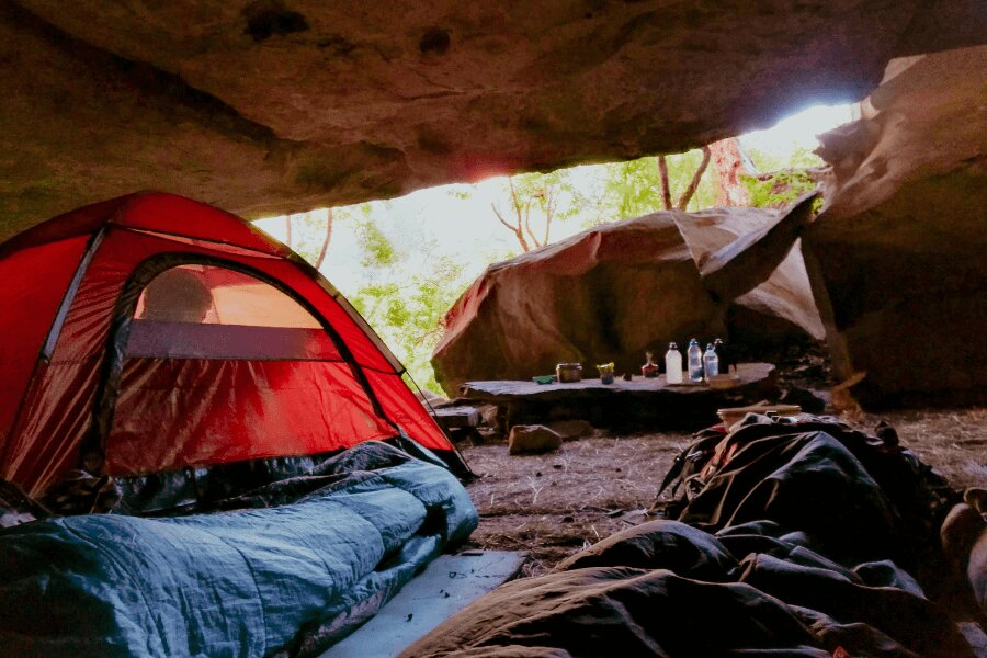 Sleeping bag and a tent under a rock overhang. Source: https://www.pexels.com/cs-cz/foto/svetly-lehky-krajina-priroda-2412023/