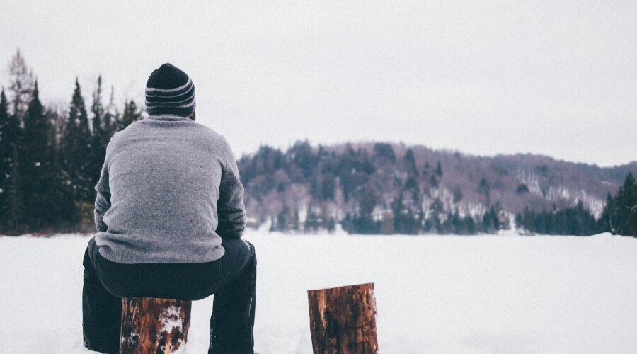 A man sits on a log in a snowy landscape