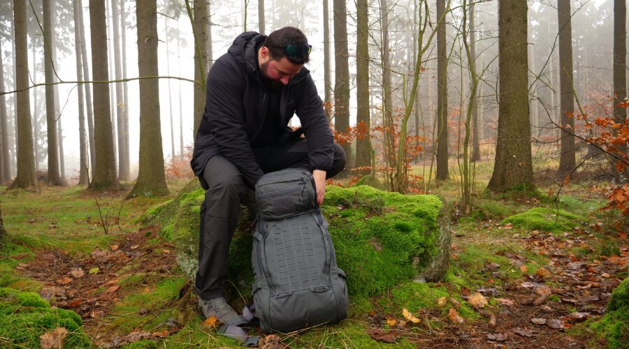 A man is packing his backpack for a trek