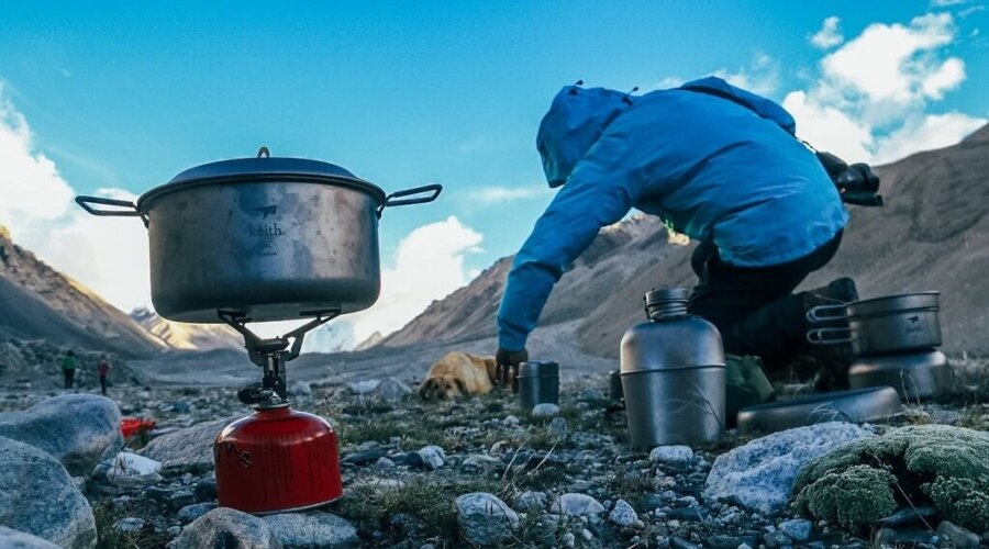 The man is cooking in outdoor cookware