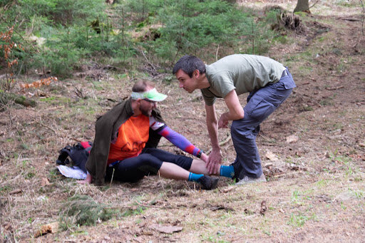 Man is checking possible limb injury of another person.