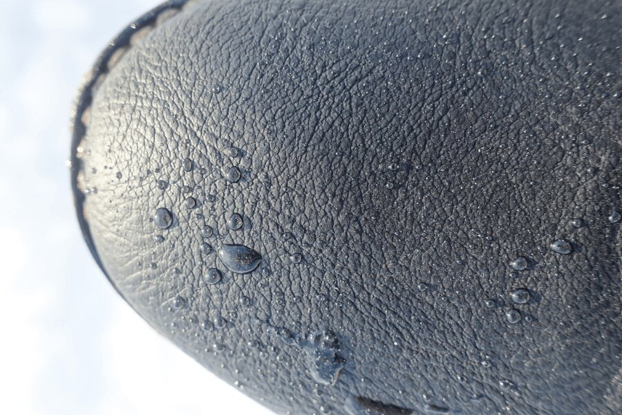 a detail of raindrops on the tip of a leather boot