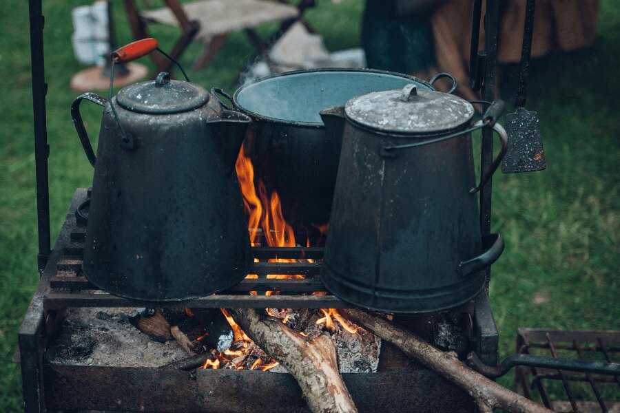 A pot and a kettle on a grill during camping