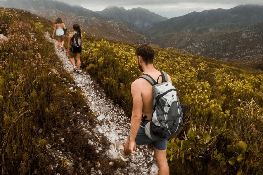 Man without shirt and two women on a mountain path