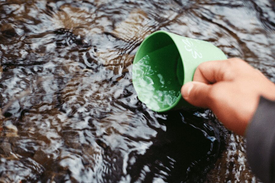 Scooping water from a stream into a green mug. Source: https://www.pexels.com/cs-cz/foto/66090/