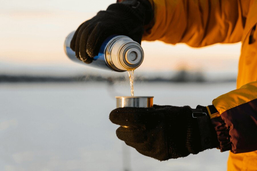 Pouring a drink from a stainless steel thermos in winter gloves. Source: https://www.pexels.com/cs-cz/foto/ruce-voda-liti-termoska-6831063/