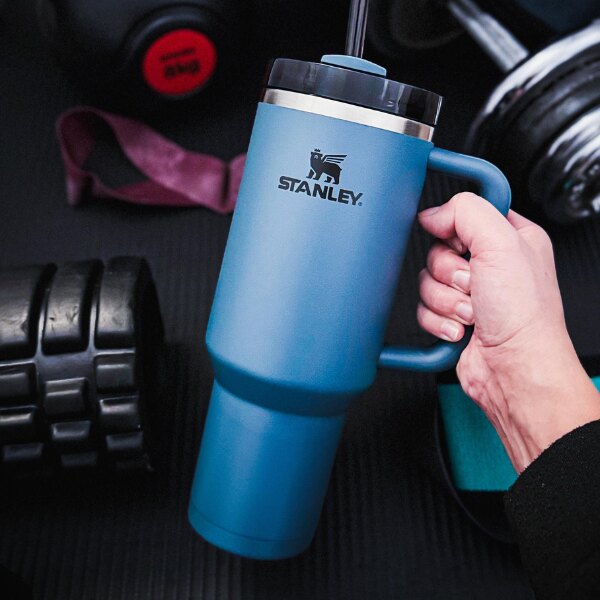 The Stanley<sup>&reg;</sup> Quencher H2.O FlowState blue thermos mug in a hand at the gym. Source: Rigad