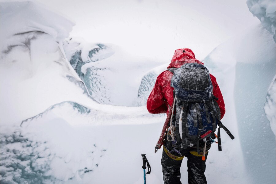 A man with a snow-covered backpack in a winter countryside. Source: https://www.pexels.com/cs-cz/foto/ryma-studeny-snih-krajina-6730946/