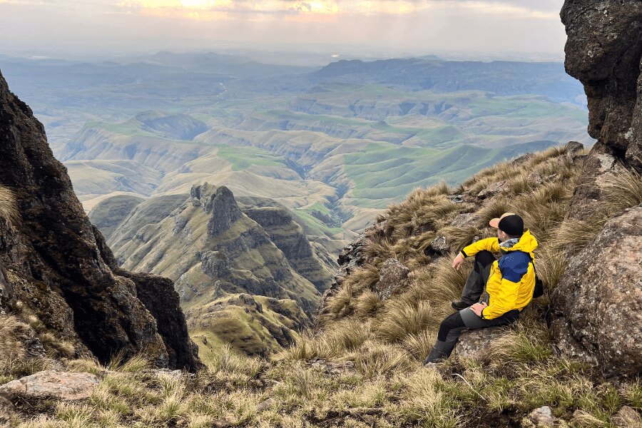 A man in a yellow outdoor jacket sitting on a slope in the Drakensberg in Africa. Photo: Author's archive