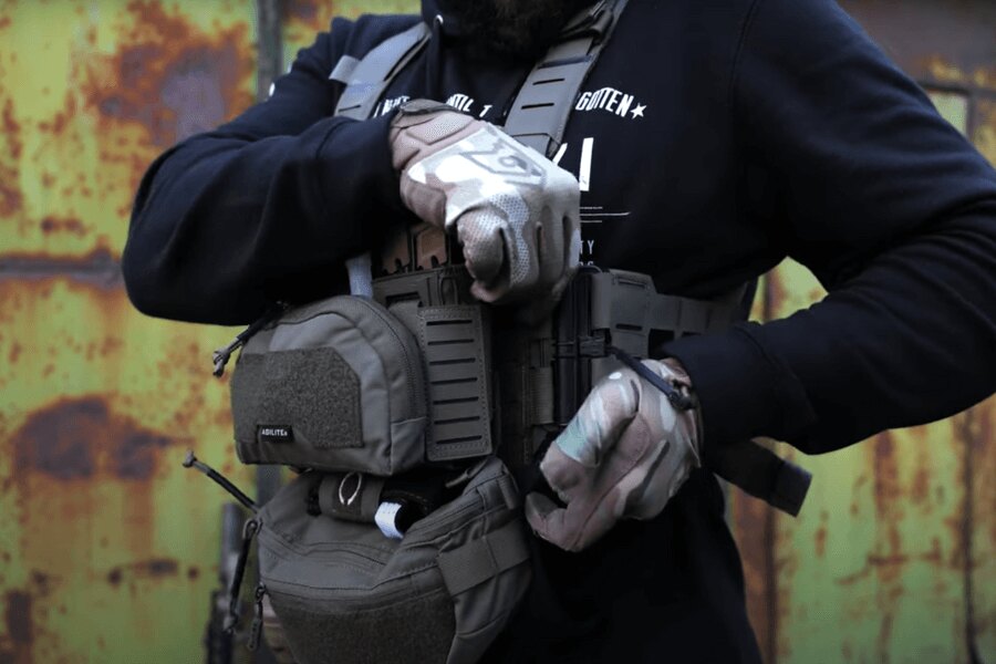 A man with the Agilite Gear<sup>&reg;</sup> Chest Rig Reaper™ fitted with pouches adjusting settings. Source: Rigad - video