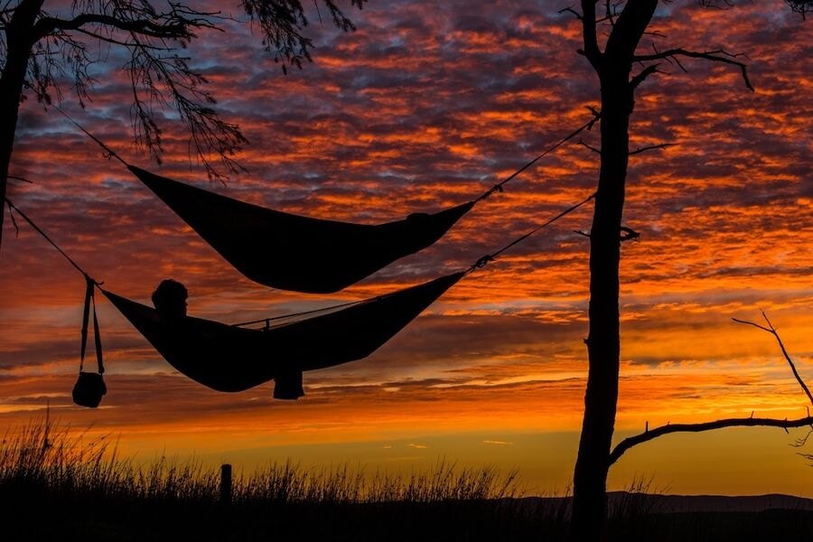 Two people lying in a hammock at sunsetTwo hanging hammocks 