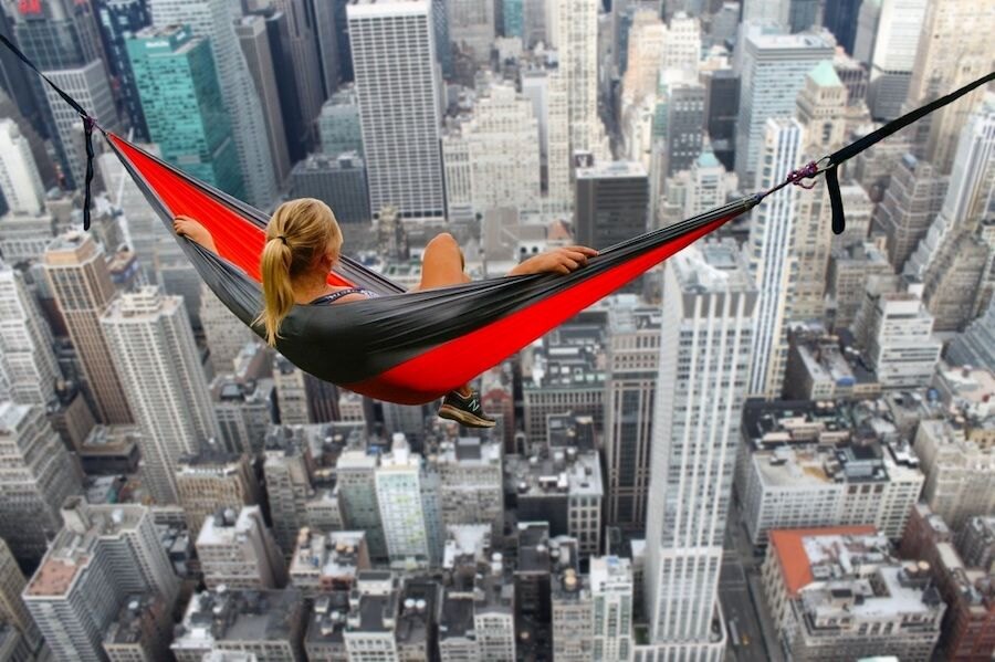 Woman lying in a hanging hammock above skyscrapers